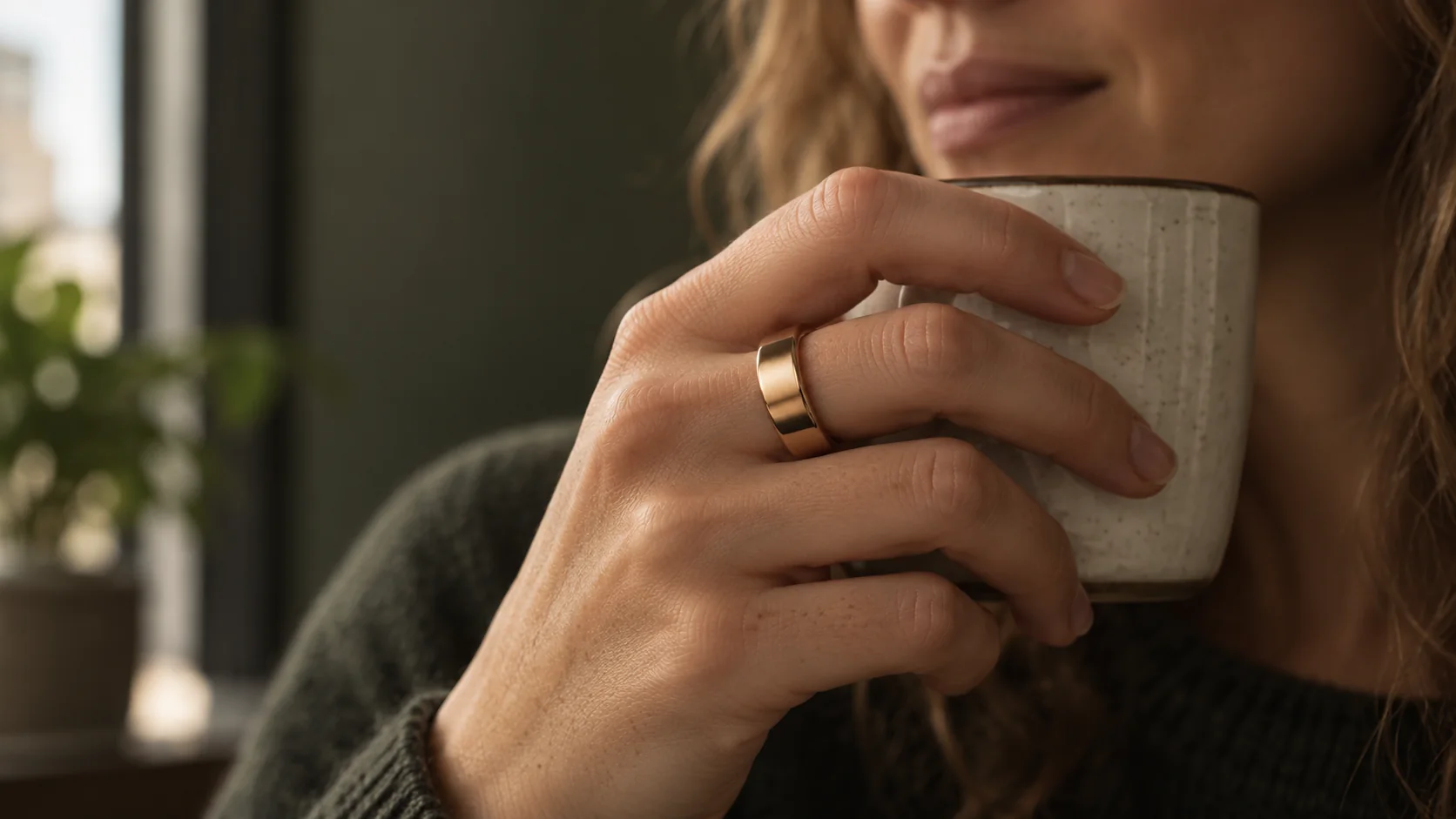Close do anel dourado na mão de uma mulher segurando uma caneca